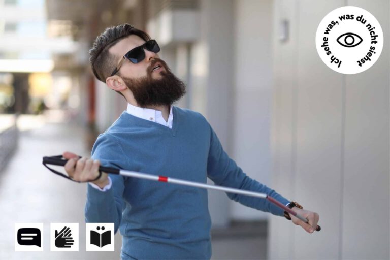 Eine Person, Männlich, mit Bart, Sonnenbrille, Blindenstock in den Händen, Auf dem Fußgängerweg