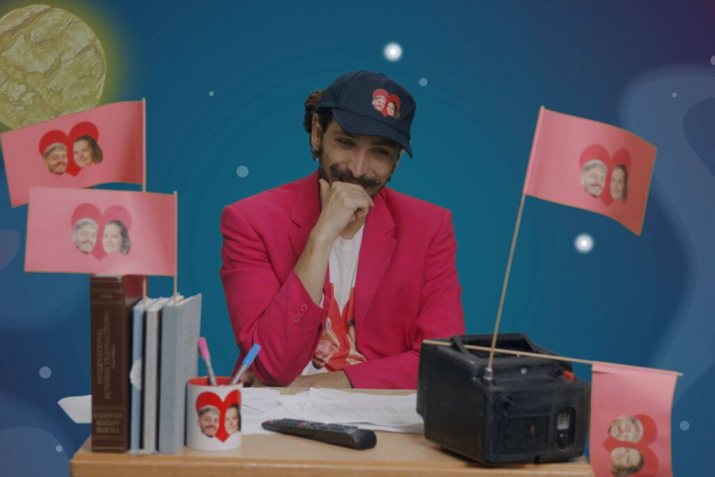 Eine Person sitzt am Schreibtisch und schaut auf einen kleinen Mini-Fernseher.